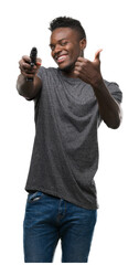 Young african american man holding a gun pointing with hand and finger up with happy face smiling