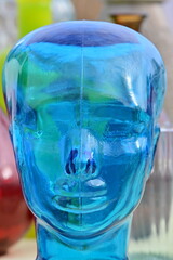 A blue glass sculpture that shows a human face.