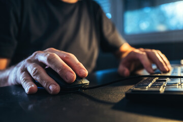 Closeup of male hands using computer mouse at home office desk, freelancer working from home.