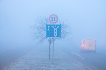Traffic in fog, road signs and vehicle on the road