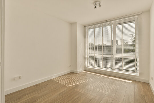 Bright empty room with large window and wooden floor