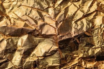 Crumpled gold colored aluminum tin foil texture as background