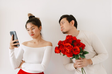 Asian man male make mistake, giving red rosed and begging for love Valentines day, woman bulk ignoring with dislike face, both standing isolated over white background wall. 