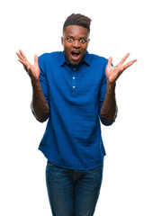 Fototapeta premium Young african american man over isolated background celebrating crazy and amazed for success with arms raised and open eyes screaming excited. Winner concept
