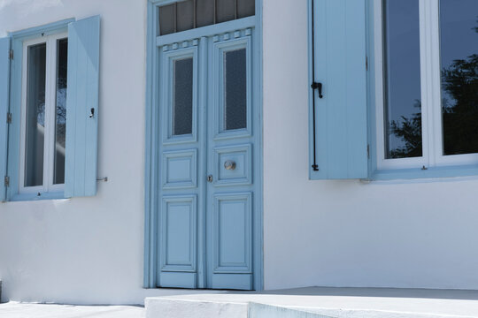 greek traditional island house with blue wooden windows and doors, whitewashed cement concrete streets and stairs