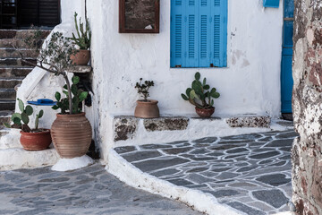 traditional greek islands street view, clay pots with plants in pennle street, whitewashed white...