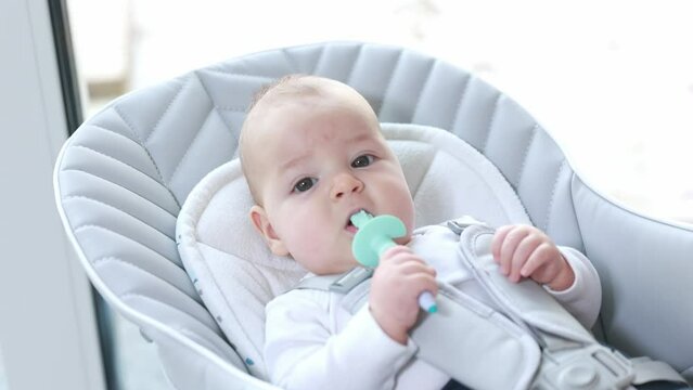 Newborn baby using a teether to ease the pain of teething, healthcare concept