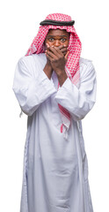 Young arabic african man wearing traditional keffiyeh over isolated background shocked covering mouth with hands for mistake. Secret concept.