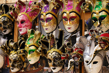 Traditional venetian masks on shelves in souvenirs shop in Venice, Italy. Beautiful carnival masks in variety of colours. Authentic and original Venetian full-face masks for Carnival. - obrazy, fototapety, plakaty
