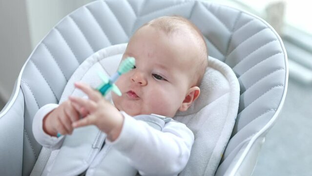 Newborn baby using a teether to ease the pain of teething, healthcare concept