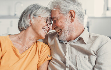 Happy laughing older married couple talking, laughing, standing in home interior together, hugging with love, enjoying close relationships, trust, support, care, feeling joy, tenderness.