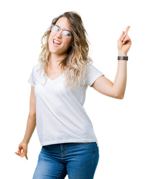 Beautiful young blonde woman wearing glasses over isolated background Dancing happy and cheerful, smiling moving casual and confident listening to music