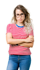 Beautiful young blonde woman wearing glasses over isolated background skeptic and nervous,...