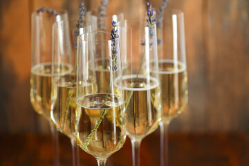 Glasses of champagne decorated with lavender on wooden background