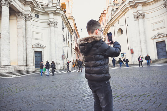 Smiling Happy tourist  boy with   eyeglasses  enjoy the city of Rome ,taking photos with a phone  at during language vacation.Concept  family travel trip happy language vacations in Rome