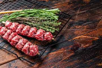 Raw kofta, kofte kebab Skewers with beef and lamb meat and spices ready for cooking. Wooden...