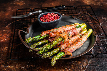Baked Prosciutto wrapped green asparagus. Dark background. Top view