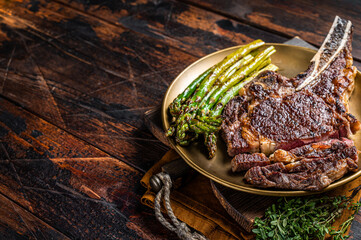 Sliced Grilled Cowboy or rib eye with bone beef steak, roasted asparagus in a plate. Wooden...