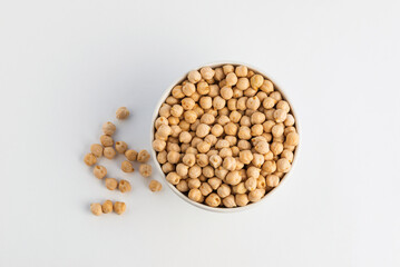 Raw uncooked chickpea in white bowl isolated on white background, top view