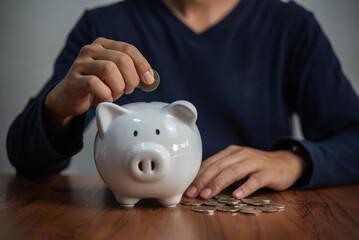 Money saving concept man holds coins and drops into a piggy bank. Business Finance, Banking and Investment Tax Accounting