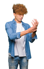 Young handsome man with afro hair wearing denim jacket Suffering pain on hands and fingers, arthritis inflammation