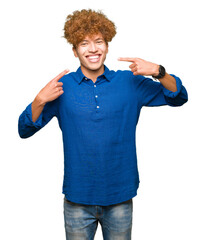 Young handsome elegant man with afro hair smiling confident showing and pointing with fingers teeth and mouth. Health concept.