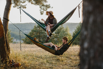 A boy and a girl rest in hammocks in the mountains. The concept of recreation and unity with nature.