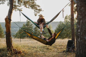A boy and a girl rest in hammocks in the mountains. The concept of recreation and unity with nature.