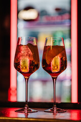Cocktail of sweet bourbon whiskey drink garnished by orange peel on bar table with blurry bokeh restaurant background. Cocktails closeup. Alcoholic cocktail with orange peel and ice isolated.