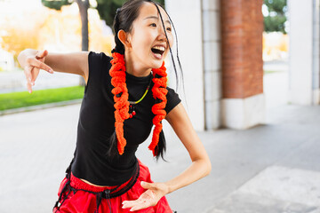 Portrait of Asian girl with special hairstyle smiling while dancing in the street, copy space