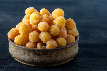 Yellow raspberries in a wooden bowl on the table. Summer berries background. Vitamin food, berry harvest. Healthy nutrition.