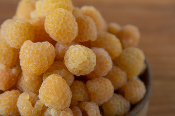 Yellow raspberries in a wooden bowl on the table. Summer berries background. Vitamin food, berry harvest. Healthy nutrition.