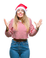 Obraz na płótnie Canvas Young beautiful woman wearing christmas hat over isolated background crazy and mad shouting and yelling with aggressive expression and arms raised. Frustration concept.