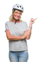 Middle age caucasian cyclist woman wearing safety helmet over isolated background with a big smile on face, pointing with hand and finger to the side looking at the camera.