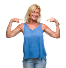 Fototapeta premium Middle age blonde woman over isolated background looking confident with smile on face, pointing oneself with fingers proud and happy.