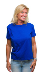 Middle age blonde woman over isolated background looking away to side with smile on face, natural expression. Laughing confident.