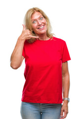 Middle age blonde woman over isolated background smiling doing phone gesture with hand and fingers like talking on the telephone. Communicating concepts.