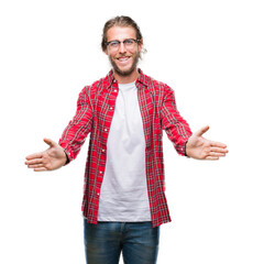 Young handsome man with long hair wearing glasses over isolated background looking at the camera smiling with open arms for hug. Cheerful expression embracing happiness.