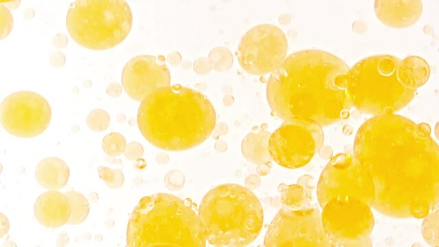 Slow Motion of Moving Yellow Golden Oil, Air Bubbles in Water Rising up on Light White Background. Transparent cosmetic gel fluid with bubbles. Macro Shot. High quality FullHD footage