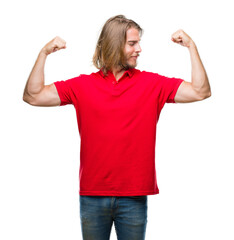 Young handsome man with long hair over isolated background showing arms muscles smiling proud. Fitness concept.