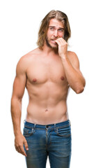 Young handsome shirtless man with long hair showing sexy body over isolated background looking stressed and nervous with hands on mouth biting nails. Anxiety problem.