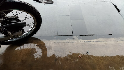 Wheel of wet motorcycle. Wet trotoar after the rain. 