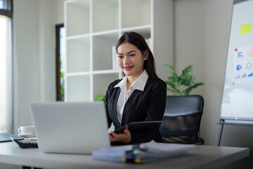Beautiful asian businesswoman woman using calculator and laptop for doing finance on an office desk, tax, report, accounting, statistics, and analysis research concept