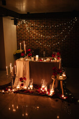 Romantic dinner setup at night. Champagne glasses, flowers. Table setting for a couple, Valentine's Day evening, burning candles for a surprise marriage proposal. Candle light date in a restaurant.