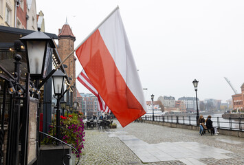 US and Polish flags fluttering in the wind on the building, old town