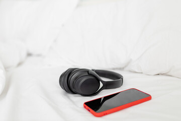 Black Headphones and smartphone over a bed. Relaxing moment concept.