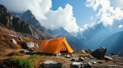 A bright orange tent in a rocky alpine environment under a clear blue sky with white clouds