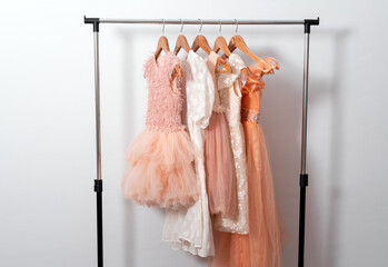 Puffy dresses hang on hanger on clothes rail on white wall background