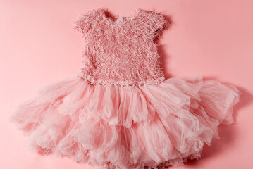 Top view flat lay pink puffy dress on pink background.