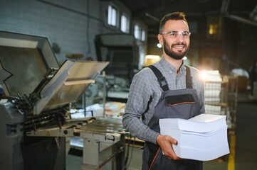 Man working in printing house with paper and paints